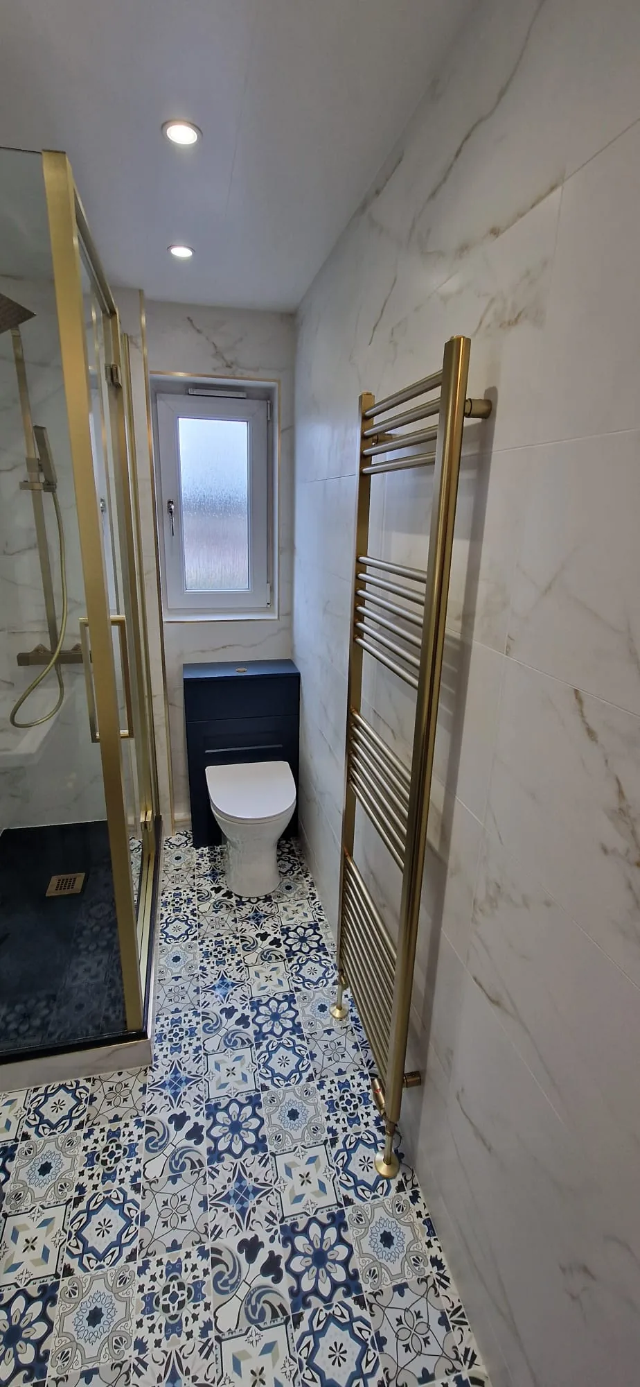 Brass-framed shower with navy furniture and patterned flooring