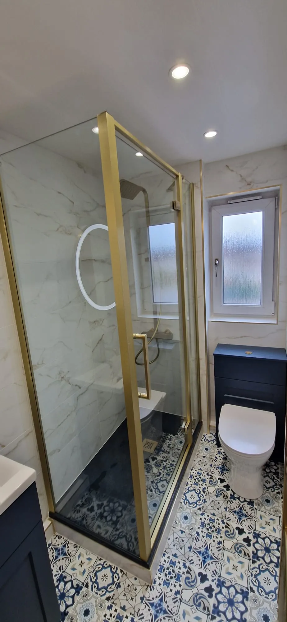 Brass-framed shower with navy furniture and patterned flooring