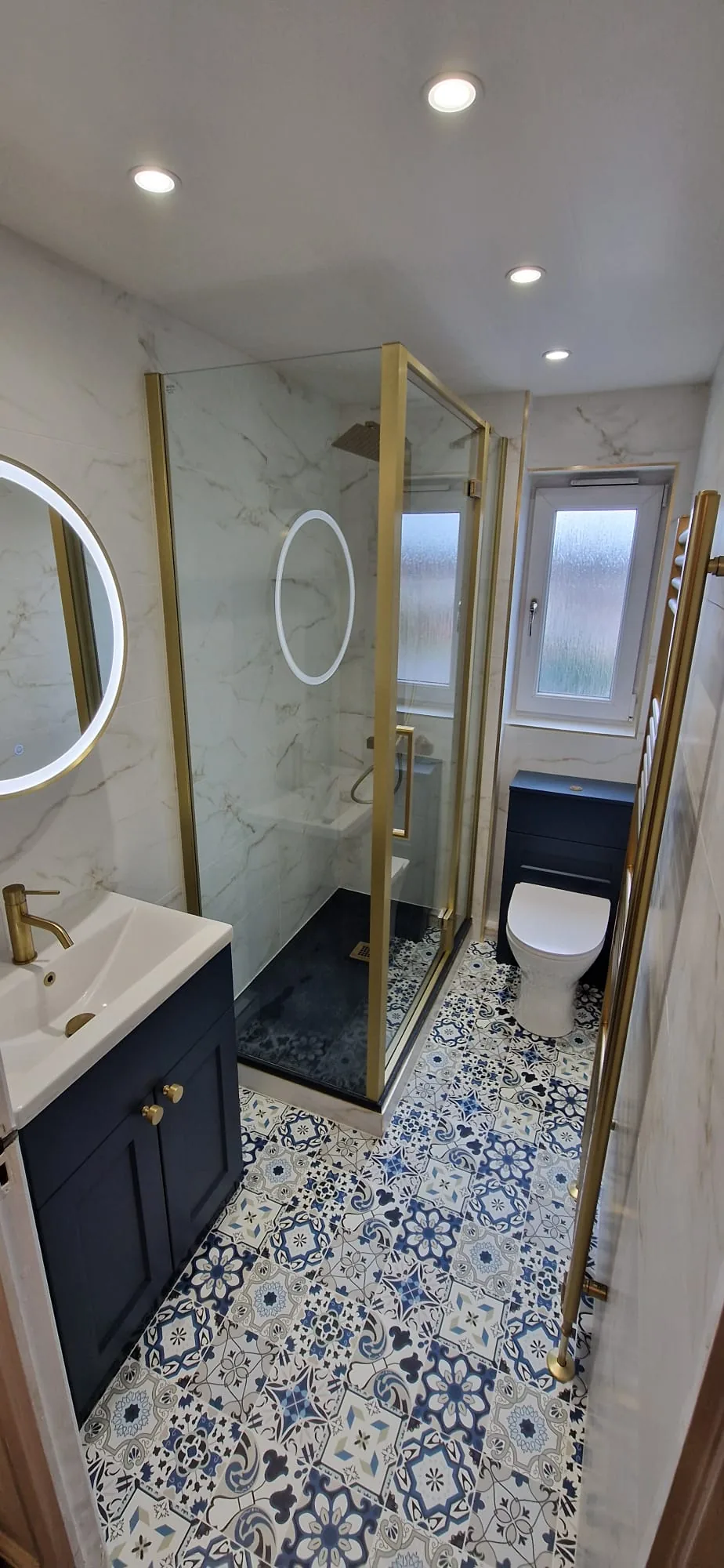 Brass-framed shower with navy furniture and patterned flooring