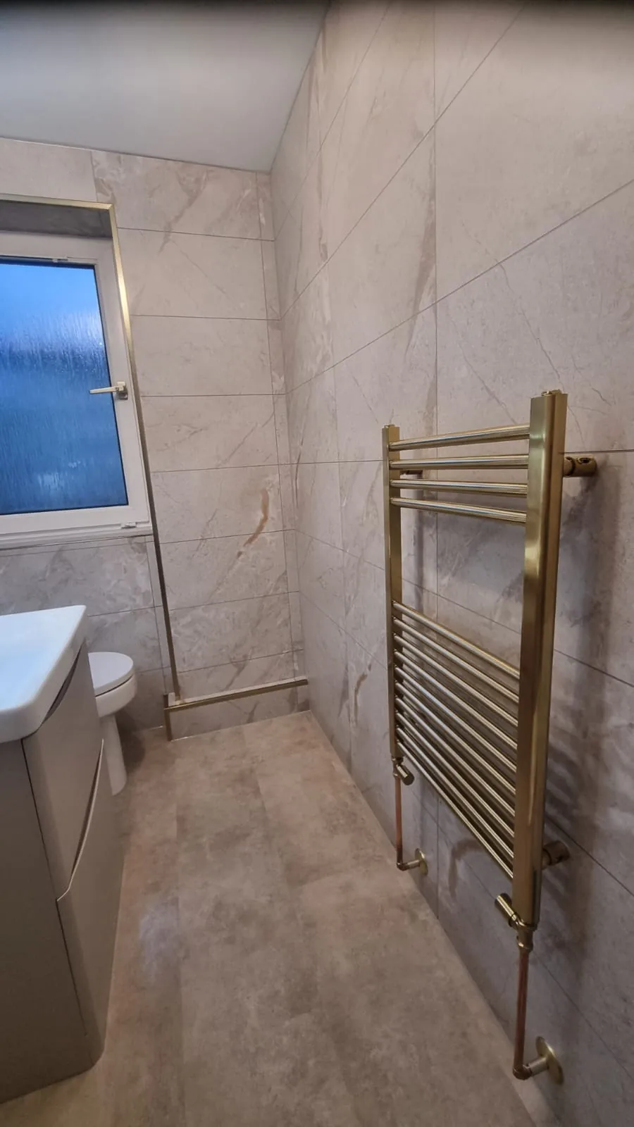 Brass towel rail against marble-effect bathroom walls